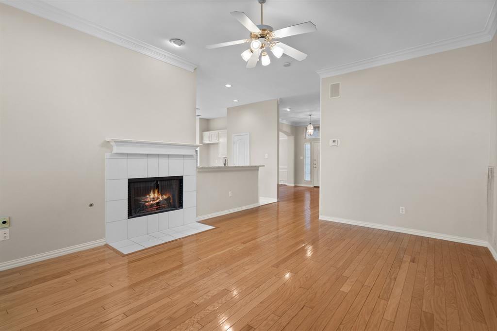 Unfurnished living room with a tile fireplace, a ceiling fan, light wood-style floors, ornamental molding, and recessed lighting