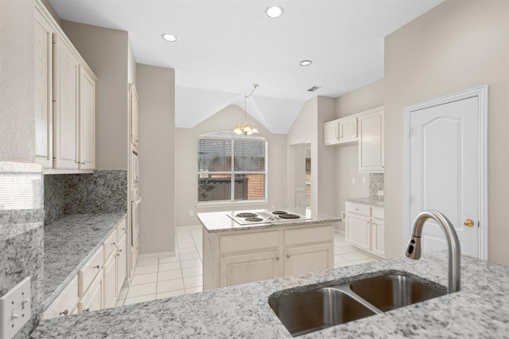 Kitchen with light tile patterned floors, a chandelier, tasteful backsplash, light stone counters, and a center island
