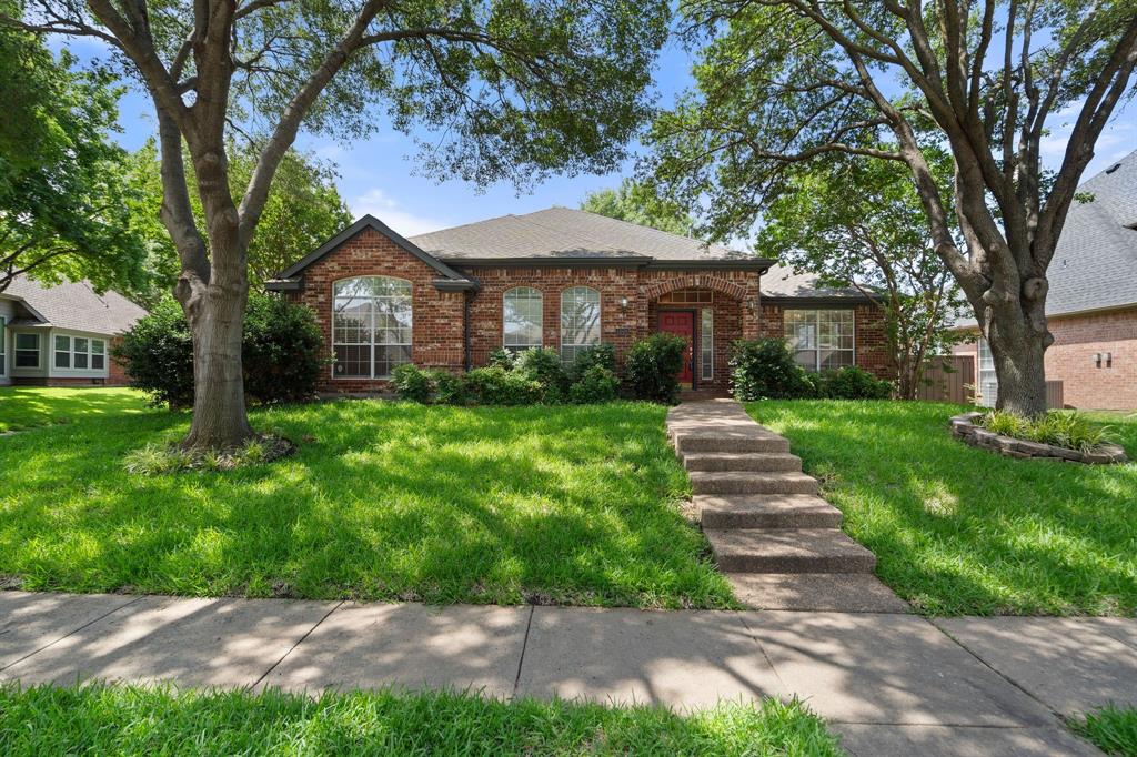 View of front of home with brick siding, a front yard, and roof with shingles