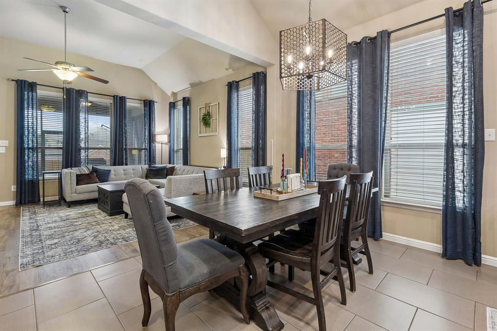 The dining area features tile flooring, an elegant decorative light fixture, large windows for natural light, and plenty of space to accommodate a full-size dining table.