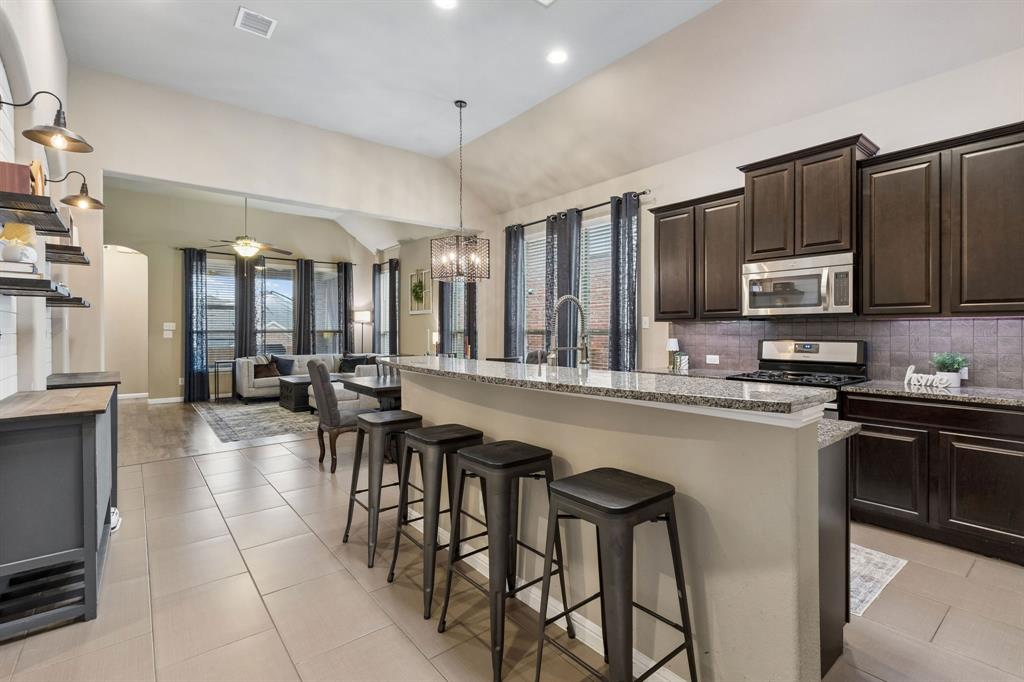 Welcome to the kitchen! Soaring ceilings, a spacious breakfast bar, and an open layout create a seamless flow into the dining and living areas.