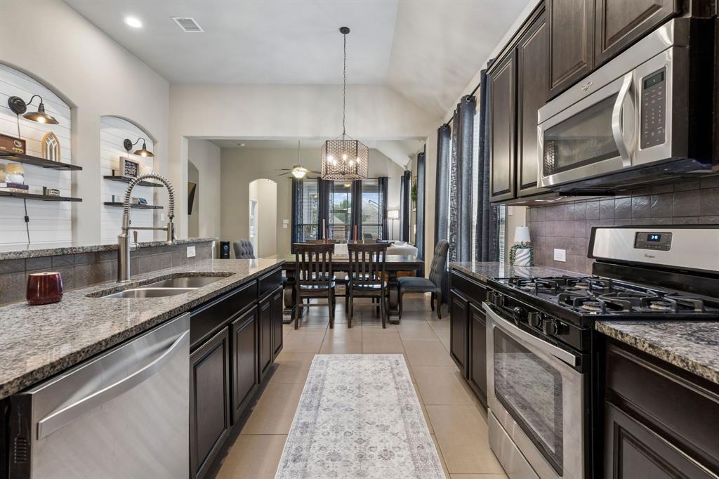 Another view highlights the stainless steel appliances, gas range, and convenient open access to the dining area.
