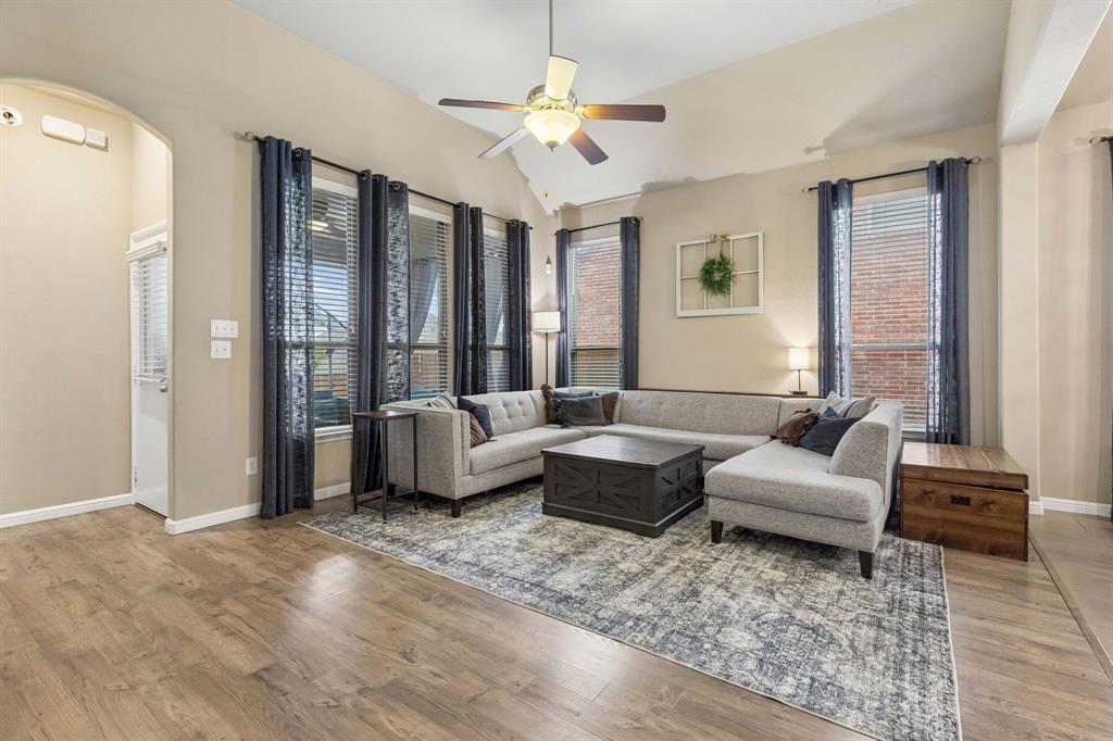 Welcome to the living room! This inviting space features high ceilings, a ceiling fan, LVP flooring, and large windows that bring in plenty of natural light.