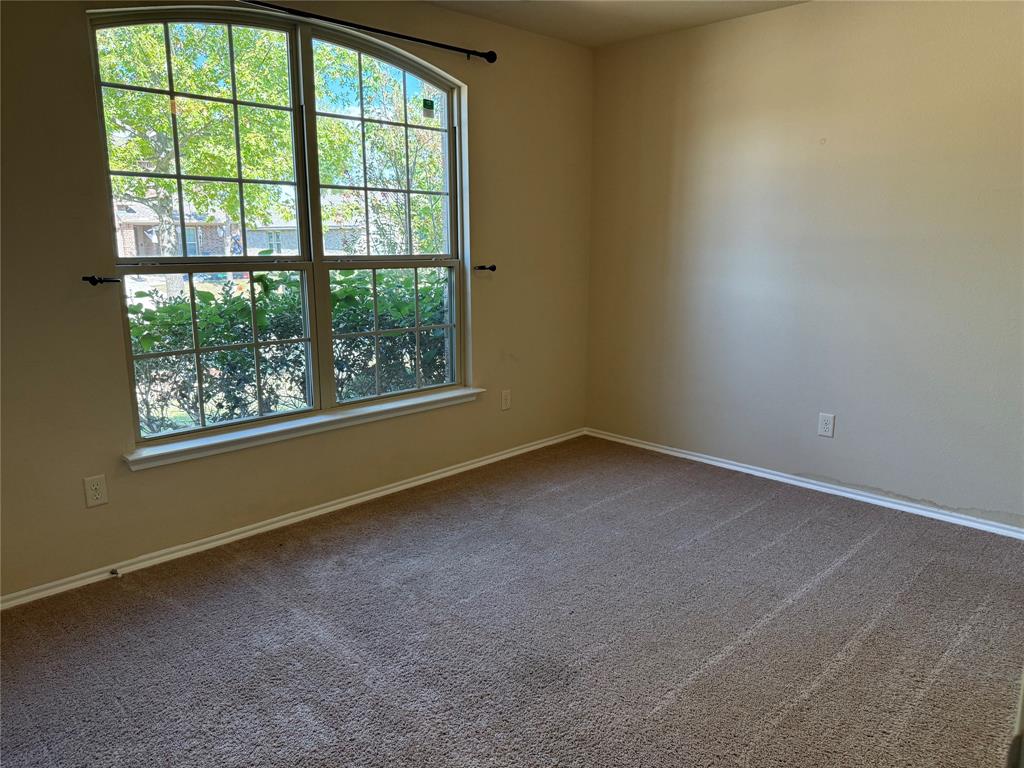 Room featuring neutral wall tones, wall-to-wall carpeting, and a large arched window with grid detailing