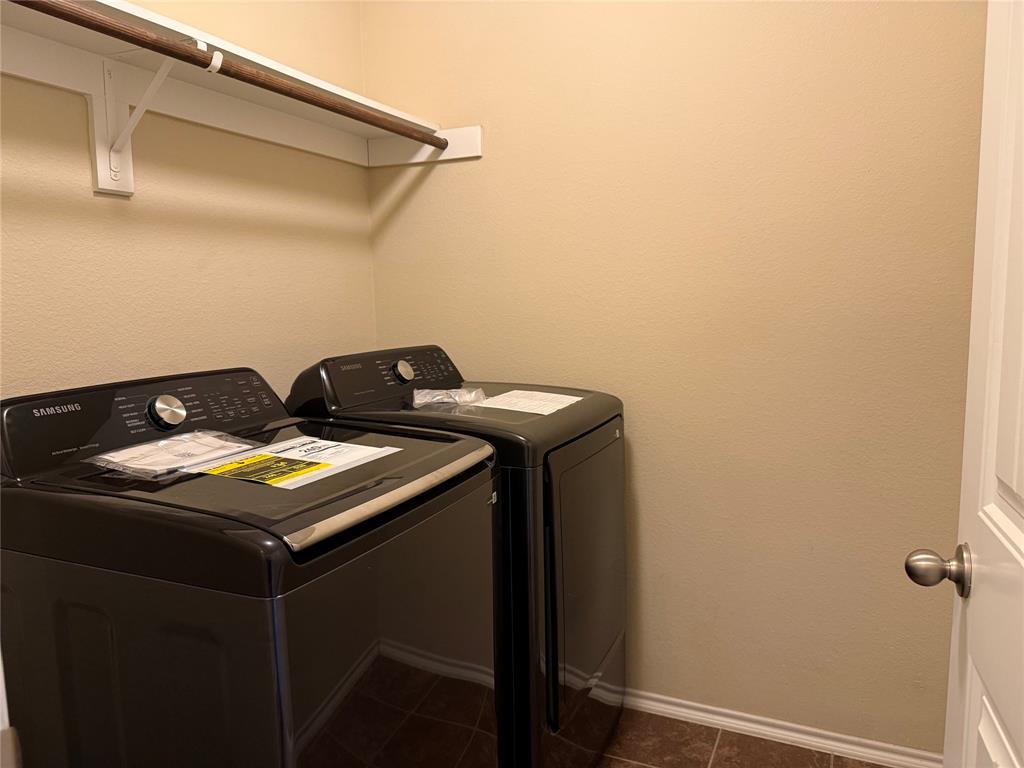 Laundry room featuring a built-in hanging rod with an integrated upper storage shelf and tiled flooring
