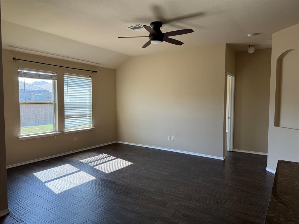 Vaulted ceilings, wood-finish flooring, dual windows with blinds, a central ceiling fan, and a recessed wall niche