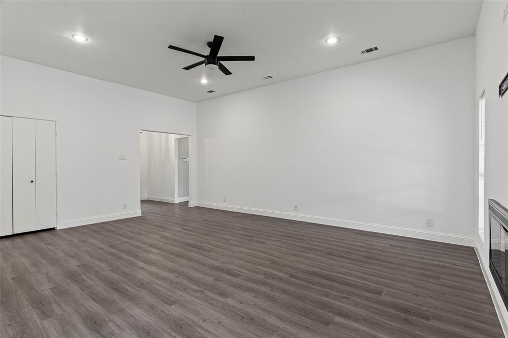 Vaulted ceilings with recessed lighting, wood-finish flooring, built-in fireplace, and matte black ceiling fan