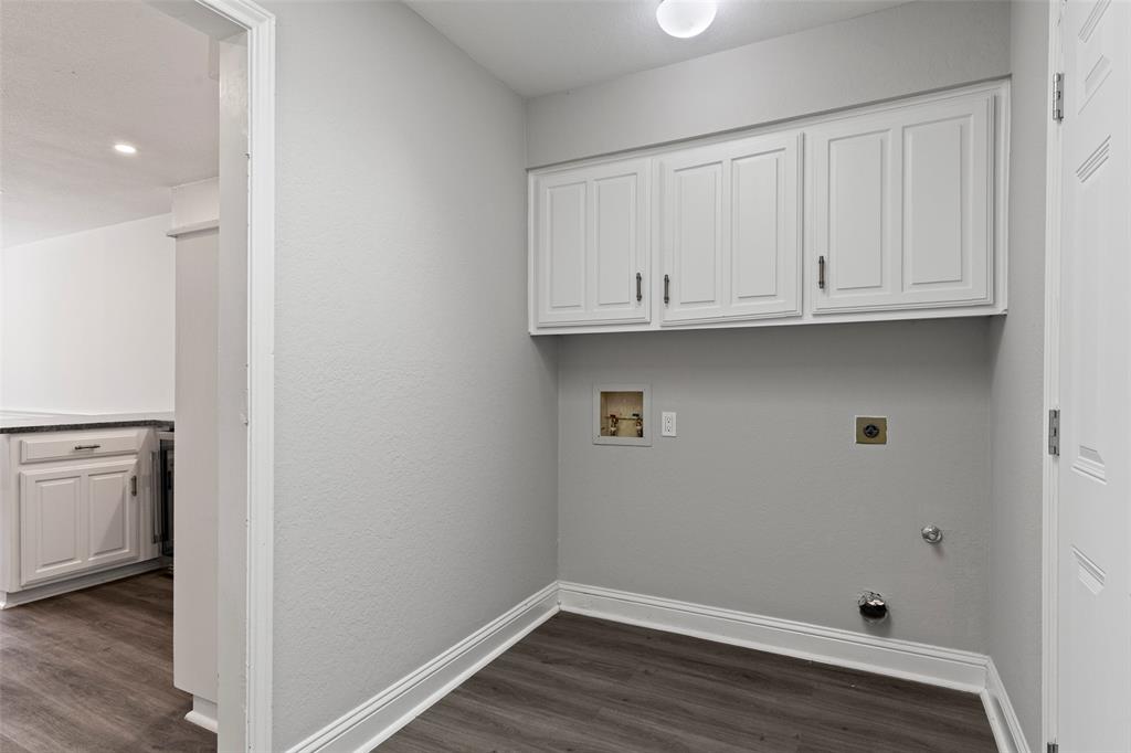 Utility area featuring white built-in upper cabinetry, wood-finish flooring, and dedicated washer and dryer hookups