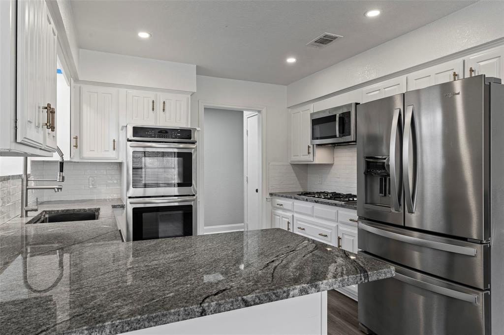 Kitchen featuring white cabinetry, granite countertops, stainless steel double wall ovens, gas cooktop, and a stainless steel french-door refrigerator