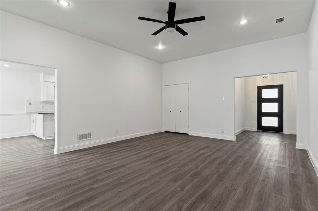 High-ceilinged interior featuring wood-finish flooring, recessed lighting, a matte black ceiling fan, and an entry door with glass panels
