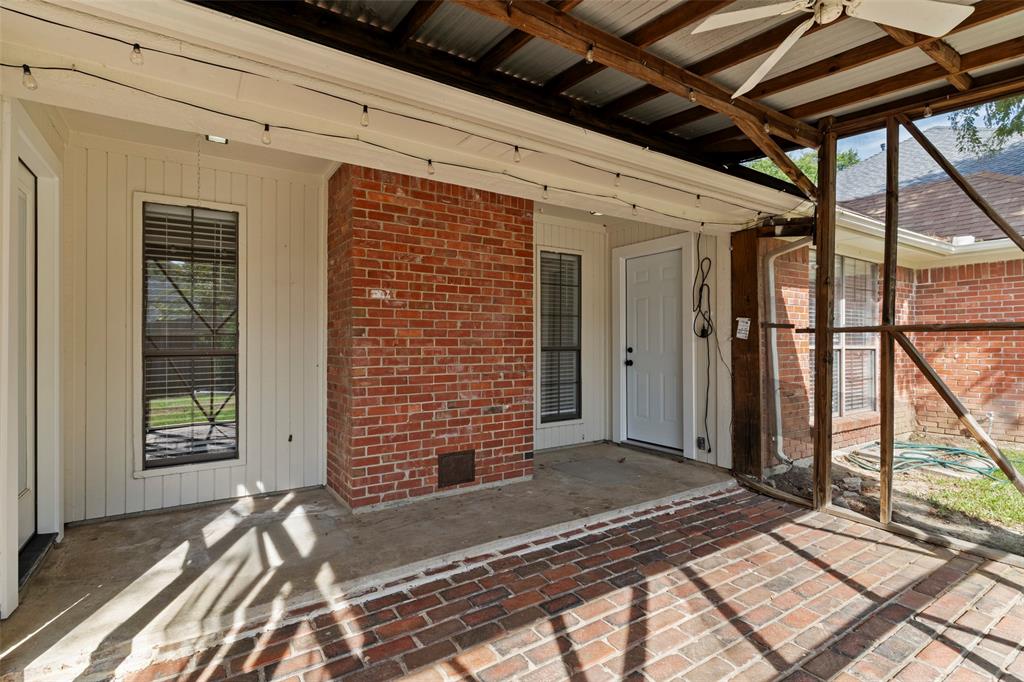 Screened-in porch featuring a brick-paved floor, exposed wood-beam ceiling with a mounted ceiling fan, and a red brick exterior accent wall