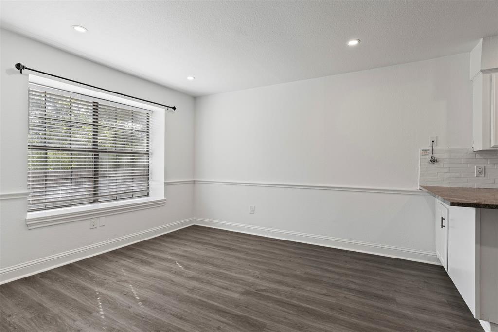Wood-finish flooring, recessed lighting, white chair rail molding, and a large window featuring horizontal blinds