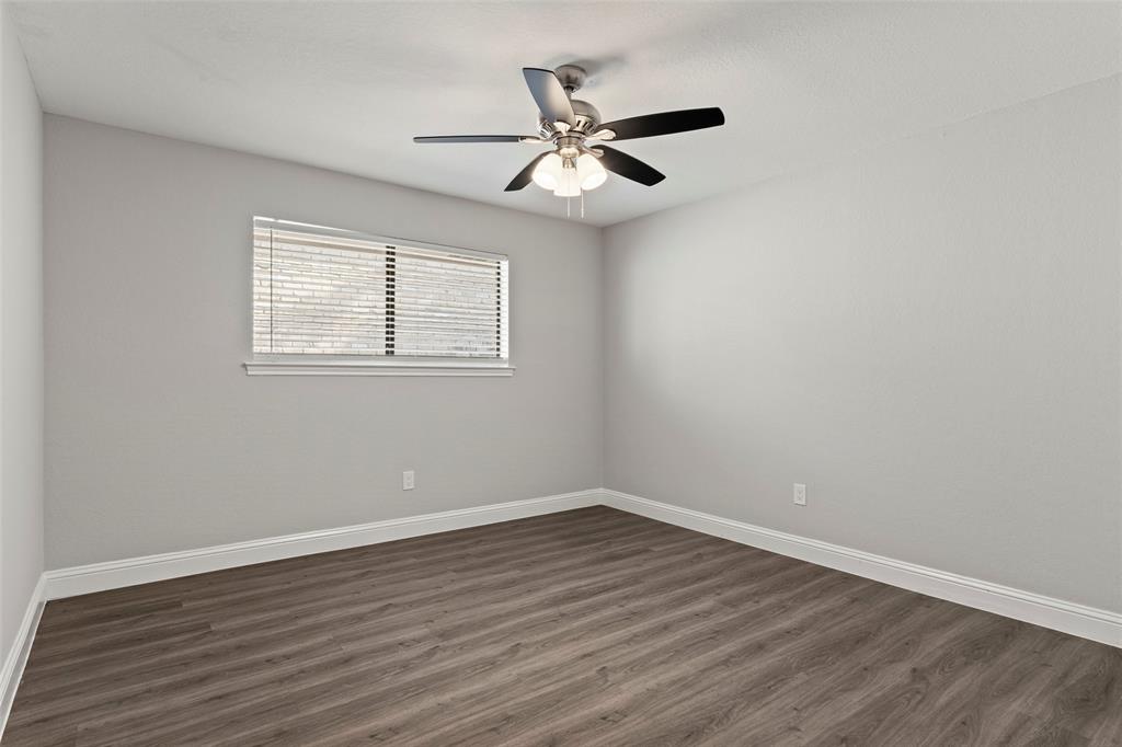 Neutral interior featuring wood-finish flooring, a ceiling fan with integrated lighting, and a window with horizontal blinds