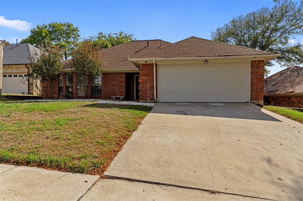 Single-story brick exterior featuring a composite shingle roof, two-car garage, and concrete driveway