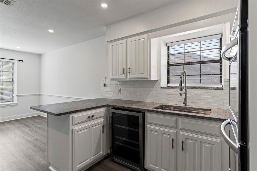 Kitchen featuring white shaker-style cabinetry, granite countertops, a white subway-tile backsplash, a stainless steel undermount sink with a gooseneck faucet, and a built-in wine refrigerator