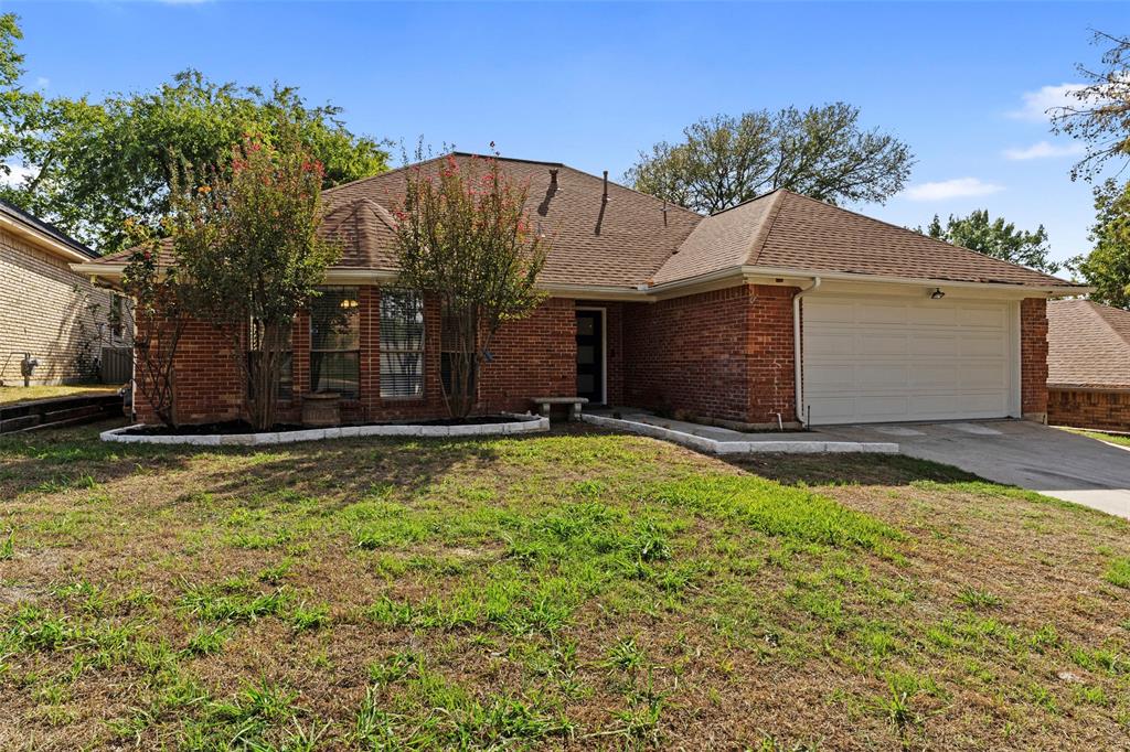 Single-story brick exterior featuring a multi-gabled roofline, an attached two-car garage, and stone-bordered landscaping beds
