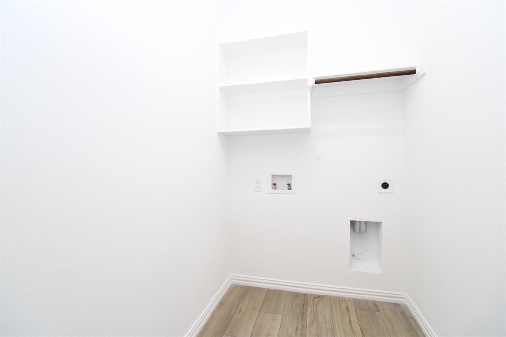 Utility area featuring wood-finish flooring, built-in white shelving, and an integrated hanging rod