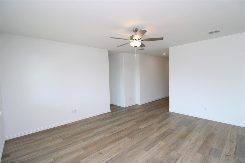 Neutral wall finishes, wood-finish flooring, and a multi-blade ceiling fan with an integrated light fixture