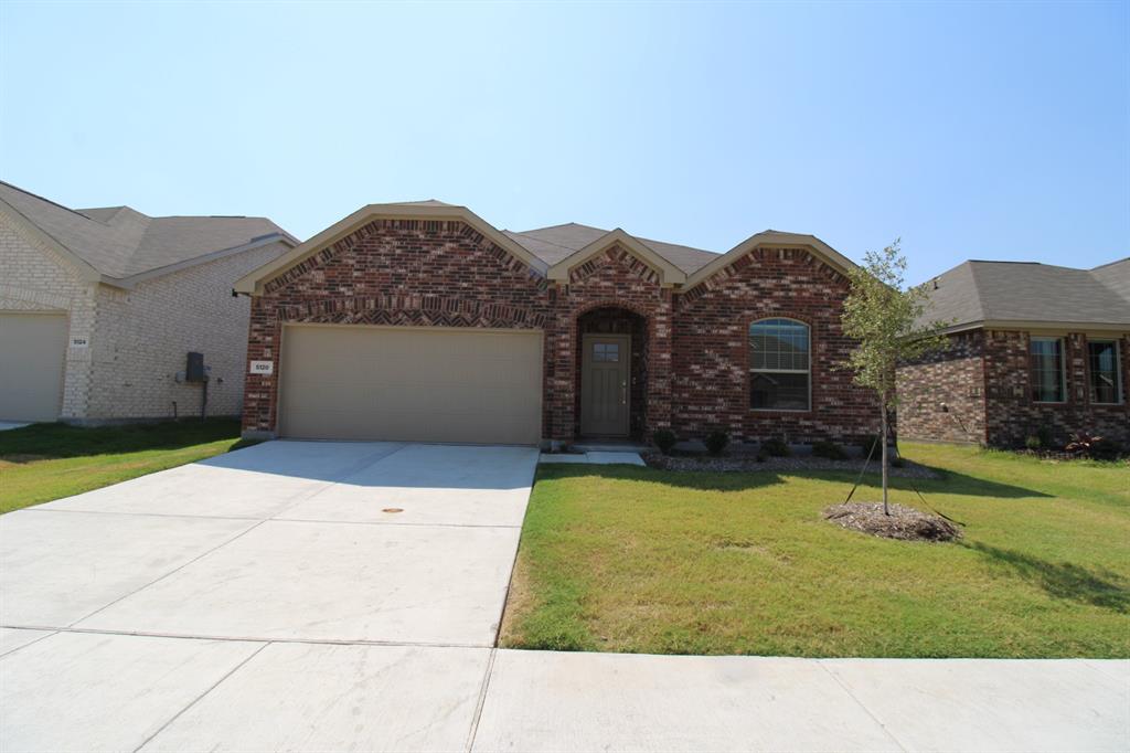 Brick exterior with multi-gabled roofline, arched entryway, concrete driveway, and attached two-car garage