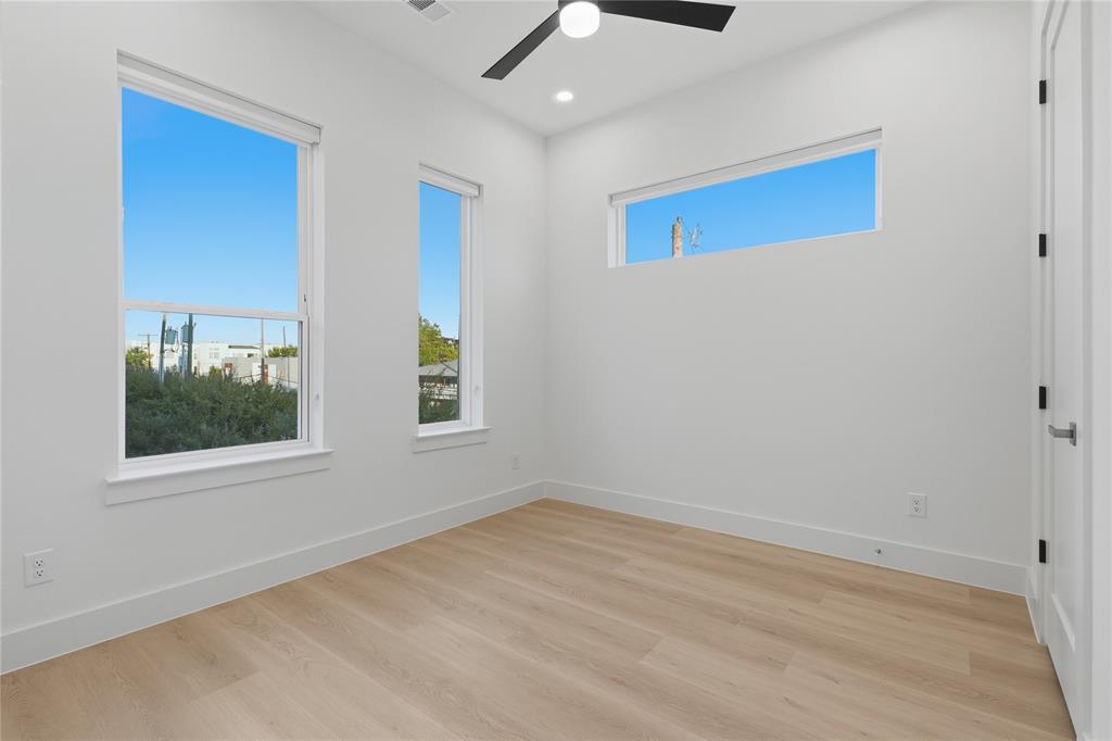 Room featuring wood-finish flooring, recessed lighting, matte black ceiling fan, and multiple windows including a rectangular clerestory window