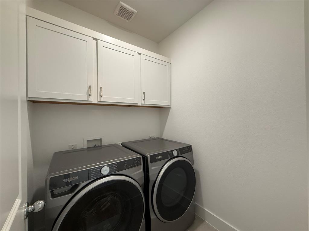 Laundry area featuring white shaker-style wall-mounted cabinetry and metallic hardware