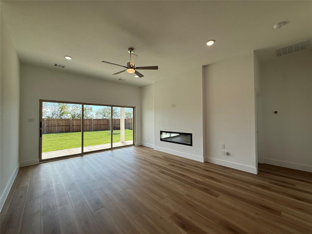 Open-concept living space featuring wood-finish flooring, recessed lighting, a modern horizontal wall-mounted fireplace, and a ceiling fan