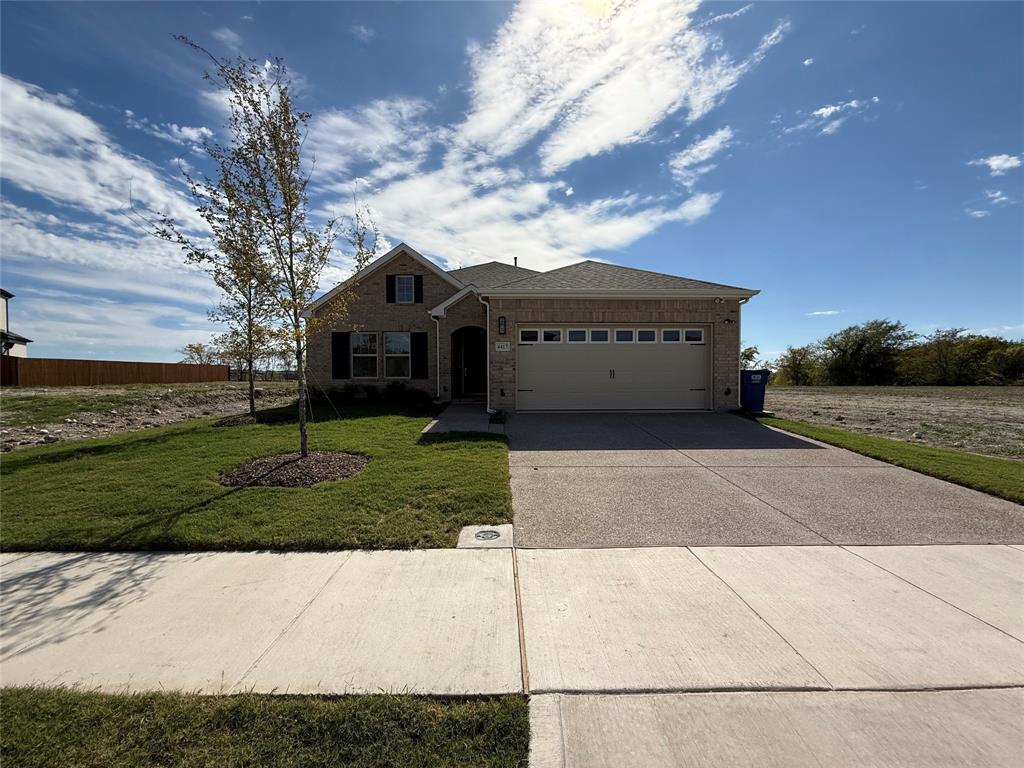 Single-story brick exterior featuring a multi-gabled roofline, an attached two-car garage with paneled door, and a concrete driveway