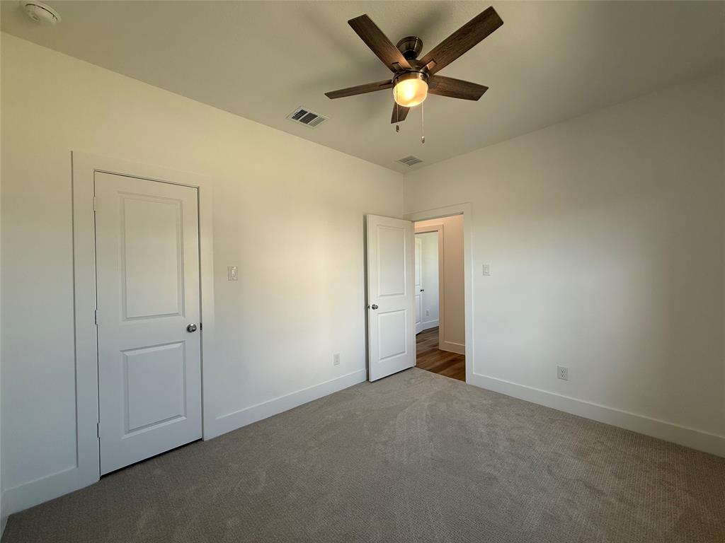Neutral-toned carpeting, two-panel interior doors, and a ceiling fan with integrated lighting