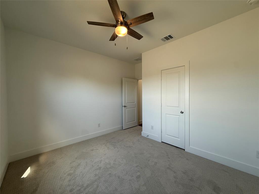 Neutral wall-to-wall carpeting, multi-panel interior doors, and a ceiling fan with integrated lighting