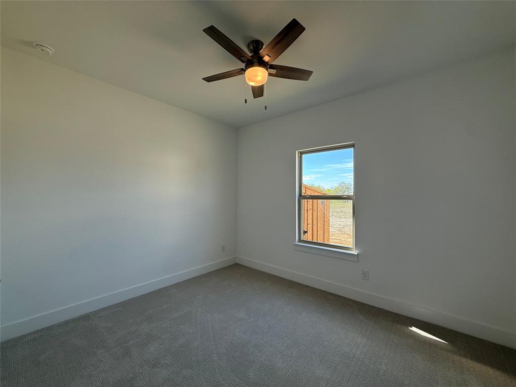 Neutral-toned wall finish, wall-to-wall carpeting, single-hung window with exterior view, and ceiling fan with integrated light fixture