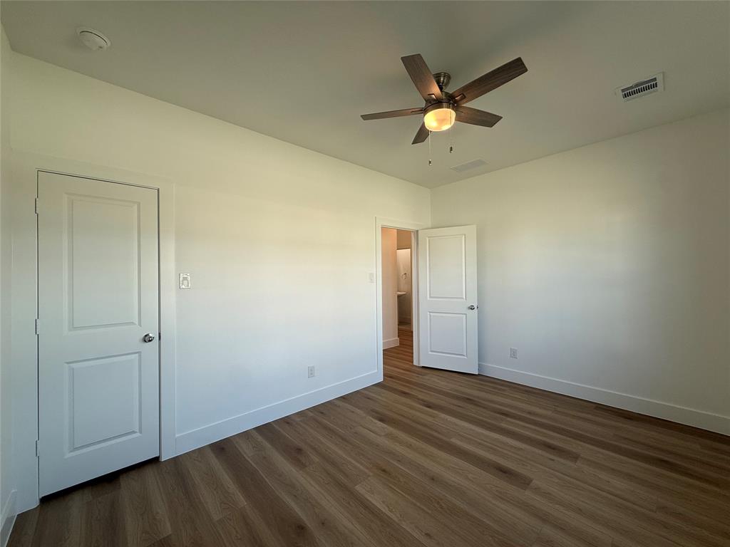 Room featuring wood-finish flooring, a ceiling fan with integrated lighting, and two-panel doors