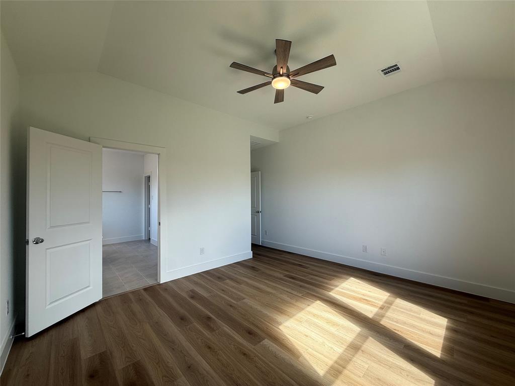 Vaulted ceiling featuring a central five-blade ceiling fan with integrated lighting and wood-finish flooring