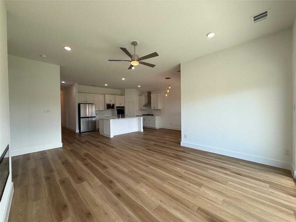 Open-concept space featuring wood-finish flooring, a central kitchen island, recessed lighting, and a multi-blade ceiling fan