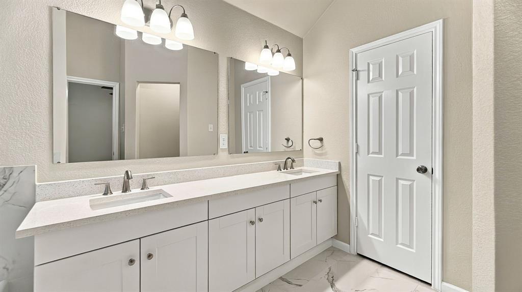 Kitchen featuring white cabinetry, light-toned stone-finish countertops, stainless steel undermount sink with arched pull-down faucet, white subway tile backsplash, and wood-finish flooring