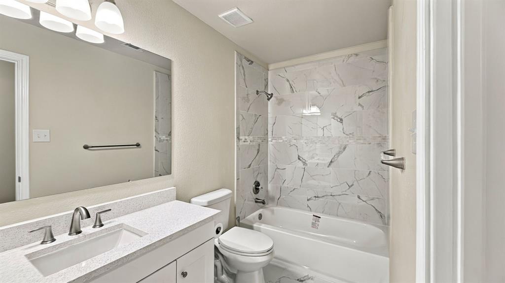 Dual-sink vanity featuring stone-composite countertops, shaker-style cabinetry, undermount sinks, and wall-mounted multi-bulb lighting fixtures