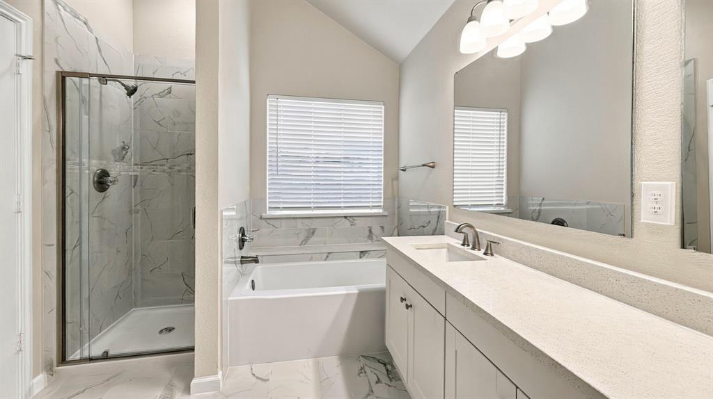 Bathroom featuring a walk-in shower with glass enclosure, soaking tub with tile surround, white cabinetry, solid-surface vanity countertop, and rectangular undermount sink