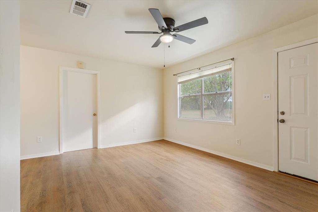 Interior room featuring wood-finish flooring, neutral wall paint, and a central ceiling fan with integrated lighting