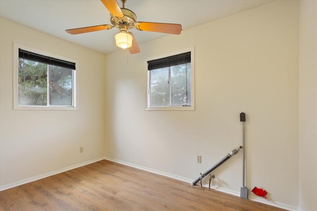 Room featuring wood-finish flooring, two sliding windows, and a ceiling fan with integrated lighting