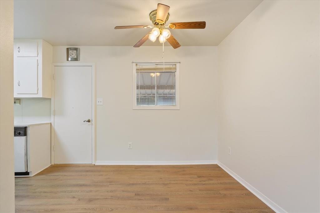 Wood-finish flooring, white cabinetry, and a ceiling-mounted light fixture with a fan