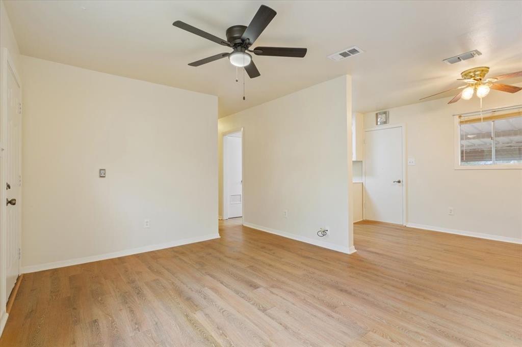 Living area featuring wood-finish flooring, two ceiling fans with integrated lighting, and a window with horizontal blinds
