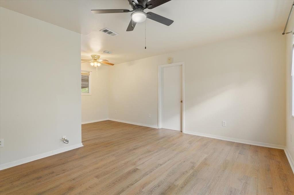 Interior space featuring wood-finish flooring, neutral wall tones, and two ceiling-mounted fans with integrated lighting