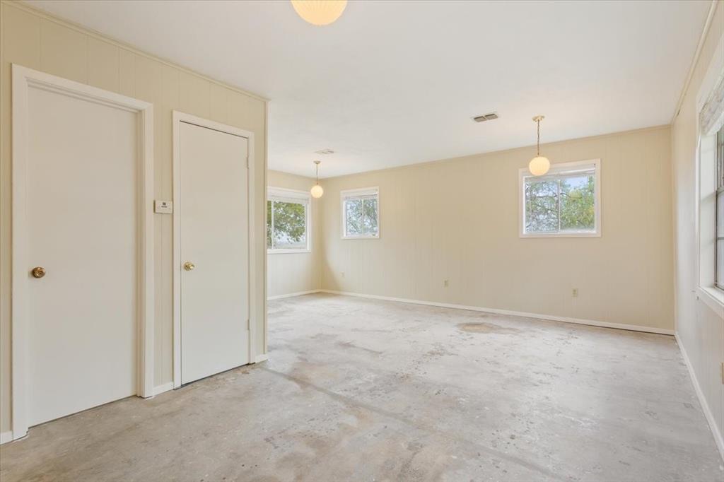 Spacious interior featuring neutral wall finishes, multiple windows, and three pendant light fixtures