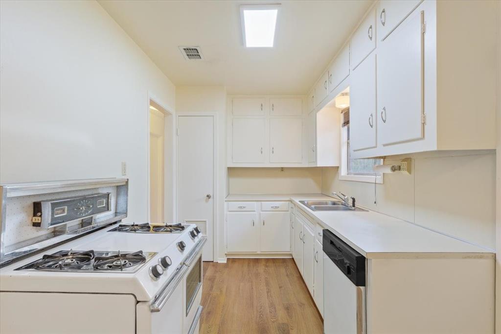 Kitchen featuring white shaker-style cabinetry, wood-finish flooring, a stainless steel sink, and a four-burner gas range