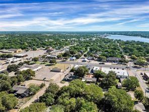 Aerial perspective featuring mature trees, paved roadways, and proximity to a large body of water