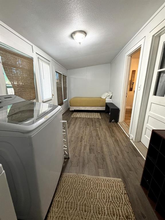 Multi-purpose space featuring wood-finish flooring, flush-mount ceiling lighting, multiple windows, and a panel door