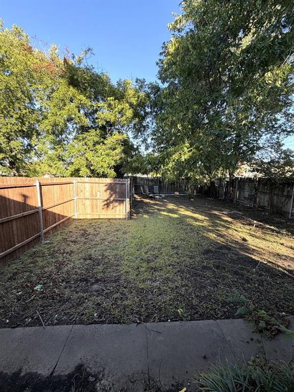 Backyard featuring a concrete patio, perimeter wood privacy fencing, and mature trees