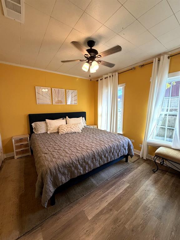Wood-finish flooring, paneled ceiling, and ceiling fan with integrated light fixture