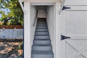 Exterior staircase with painted treads, handrail, and white picket fencing