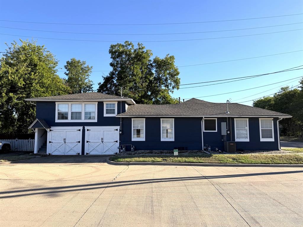 Two-story exterior featuring dark-toned siding, white trim, dual carriage-style garage doors, and an asphalt shingle roof