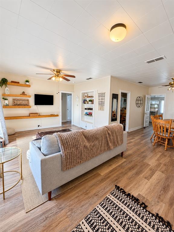 Wood-finish flooring, built-in wall shelving, wood-accent floating shelves, and ceiling-mounted light fixtures